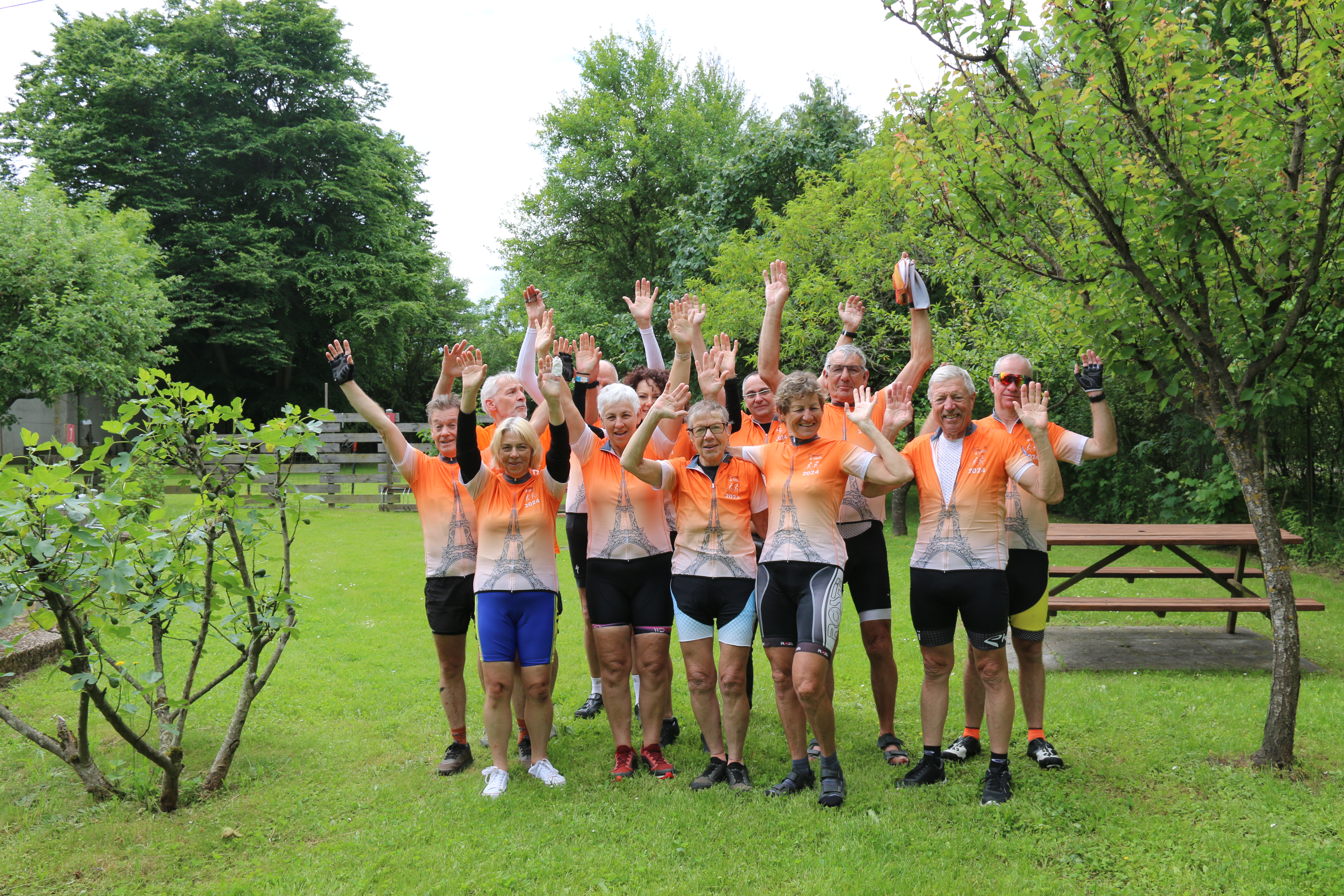 les  participants sont groupés et lèvent les bras avec un fond végétal